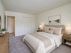 Lumberton apartment for rent - A bedroom with a large bed, a wooden nightstand, and a painting on the wall.