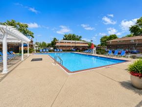 Voorhees apartment for rent - A large swimming pool surrounded by blue lounge chairs and a white pergola.