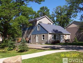 Kalamazoo house for rent - A house with a blue roof and a white door is surrounded by greenery.
