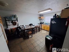 Kalamazoo house for rent - A kitchen area with a table and chairs, a refrigerator, and a counter with various items on it.