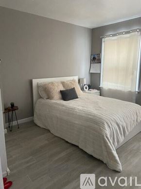 Kalamazoo house for rent - A bedroom with a large bed and a window with white curtains.