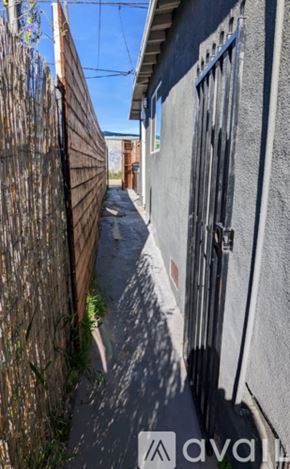 San Diego apartment for rent - A narrow alley with a wooden fence on the left and a grey building on the right.