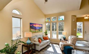 Arvada house for rent - A living room with a couch, a chair, a table with a lamp and a painting on the wall.