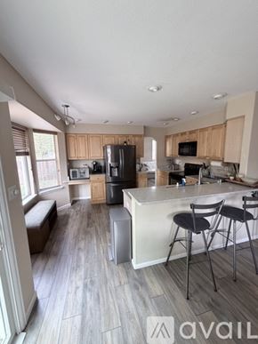 Arvada house for rent - A kitchen with wooden cabinets and a white island with two stools.