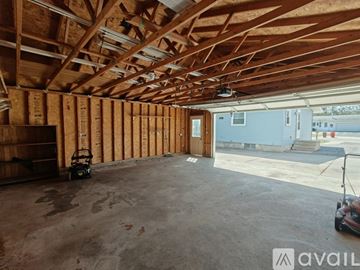 Altoona house for rent - A spacious garage with wooden walls and ceiling, a concrete floor, and a small workbench.