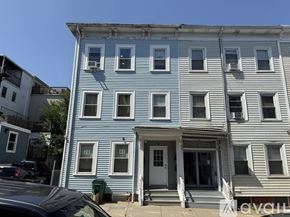 Boston apartment for rent - A blue and white two story building with a car parked in front.