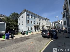 Boston apartment for rent - A street view of a blue building with cars parked in front.