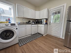 Boston apartment for rent - A small, clean, and well-organized kitchen with white cabinets and a washer and dryer.