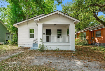 Jacksonville house for rent - A small white house with a porch is surrounded by trees.