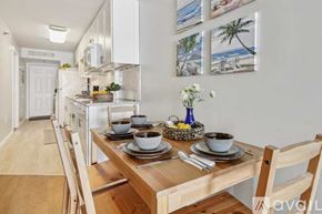 North Myrtle Beach house for rent - A dining table set with plates and bowls is in the foreground of a kitchen.