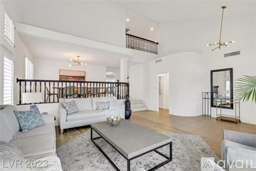 Henderson house for rent - A spacious living room with a white sofa set, a grey coffee table, and a staircase with a black railing.