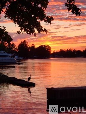 Brewerton house for rent - A bird is standing on a dock in the water during sunset.