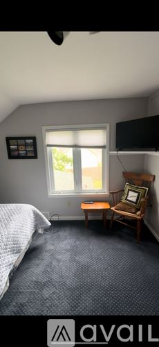 Brewerton house for rent - A bedroom with a bed, a chair, and a window.