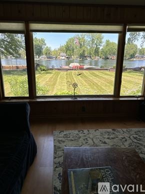 Brewerton house for rent - A room with a large window overlooking a grassy field and a body of water.