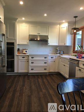 Brewerton house for rent - A kitchen with white cabinets and a wooden floor.