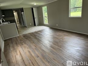 Zebulon house for rent - A spacious room with wooden flooring and a kitchen area to the left.