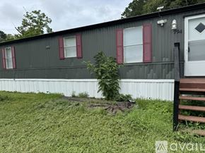 Zebulon house for rent - A grey building with red shutters and a white door.