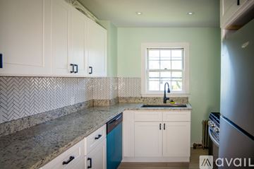 Danvers house for rent - A kitchen with white cabinets and a marble countertop.