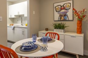 Davie apartment for rent - A dining room with a white table and chairs, a bowl, a glass, and a painting of a frog with glasses.