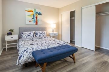 Davie apartment for rent - A bedroom with a large bed and a blue ottoman.