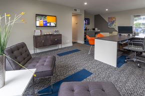 Davie apartment for rent - A modern office space with a white desk, black and grey chairs, and a TV mounted on the wall.