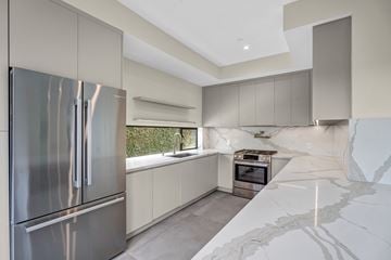 Los Angeles house for rent - A modern kitchen with a stainless steel refrigerator and marble countertops.