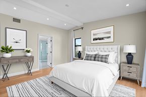 Los Angeles house for rent - A well-lit bedroom with a large bed, a nightstand, and a table with a plant on it.
