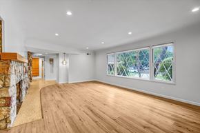 Northridge house for rent - A spacious room with wooden floors and a stone wall.