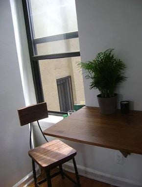 New York apartment for rent - A wooden chair sits in front of a window with a potted plant on the table.