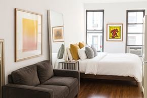 New York apartment for rent - A bedroom with a bed, a couch, and a painting on the wall.