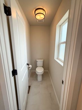 Colorado Springs house for rent - A white toilet in a small bathroom with a light on the ceiling.