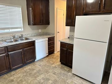 Bay City apartment for rent - A white refrigerator stands in a kitchen with dark wood cabinets.