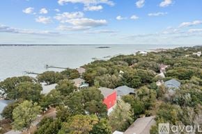 Emerald Isle house for rent - A bird's eye view of a residential area with houses surrounded by trees and a body of water in the distance.