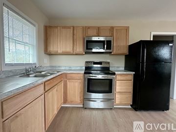 Rocky Mount house for rent - A kitchen with wooden cabinets and a black refrigerator.