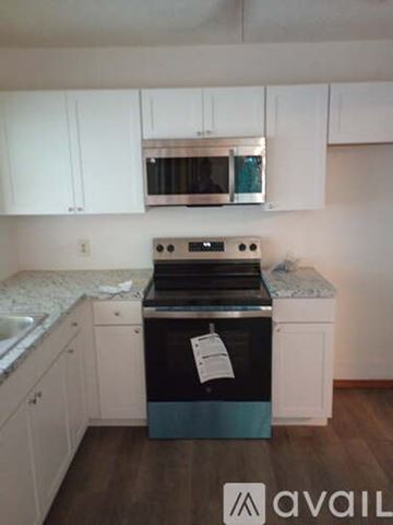 Lawton house for rent - A kitchen with a stove top oven and white cabinets.