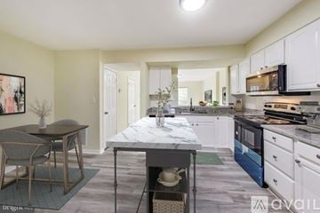 Triangle house for rent - A kitchen with a table and chairs in the foreground and a dining area in the background.