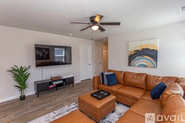 Ocean Isle Beach house for rent - A living room with a brown leather couch and a ceiling fan.