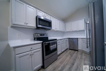 Montgomery house for rent - A kitchen with white cabinets and a black microwave above the stove.