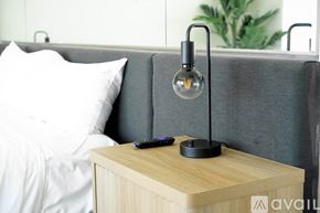 Las Vegas apartment for rent - A modern bedroom with a grey headboard and a wooden nightstand with a lamp on it.