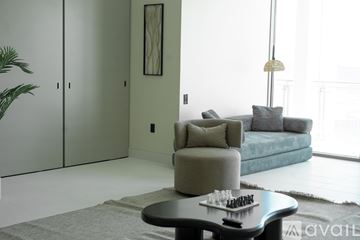 Las Vegas apartment for rent - A living room with a grey armchair, a blue couch, a coffee table with a chess set on it, and a large window.