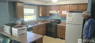 Middletown apartment for rent - A man stands in a kitchen with a refrigerator and a stove.