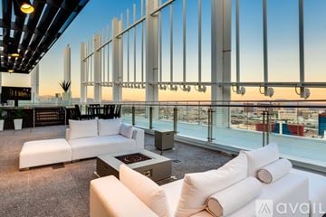 Las Vegas apartment for rent - A modern living room with white furniture and a view of the city at dusk.