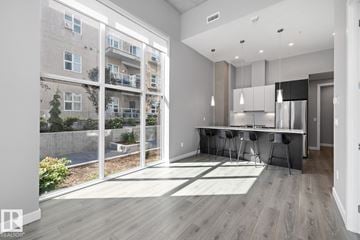 Edmonton townhouse for rent - A modern kitchen with a dining table and chairs is visible through a glass wall.