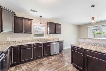 Hubert house for rent - A kitchen with dark brown cabinets and a granite countertop.