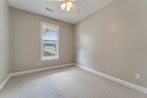 Jacksonville house for rent - A room with a ceiling fan and a window showing a view of a house and trees.
