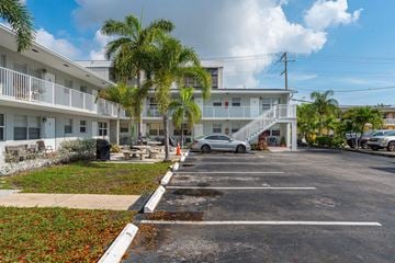 Lake Worth Beach apartment for rent - A parking lot in front of a white building with a silver car parked in the lot.