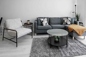 Winnipeg apartment for rent - A grey couch with a white chair and a glass table in a room.