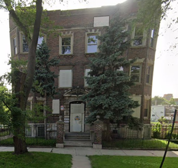 Chicago apartment for rent - A brick building with a black fence and a tree in front.