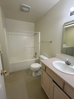Grandview apartment for rent - A white toilet is in a bathroom with a sink and mirror.