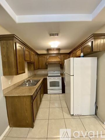 Mc Allen apartment for rent - A kitchen with wooden cabinets and a white refrigerator.